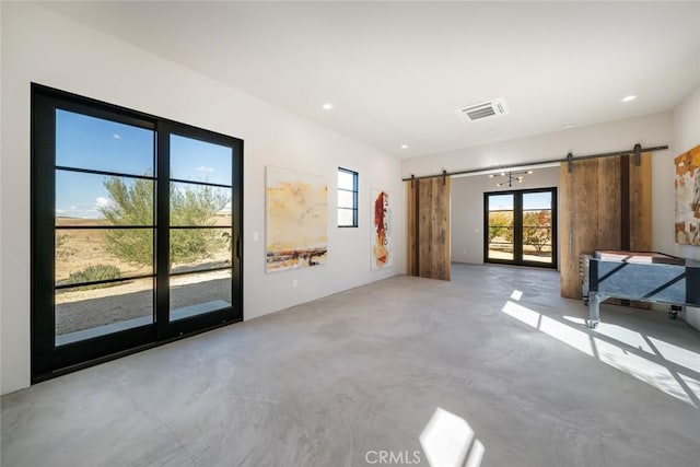 unfurnished living room featuring concrete flooring and a barn door