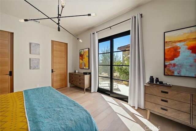 bedroom featuring an inviting chandelier, access to exterior, and light hardwood / wood-style flooring