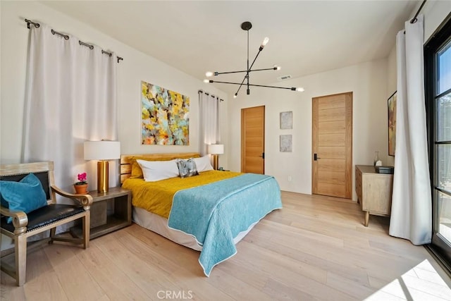 bedroom with light wood-type flooring and an inviting chandelier