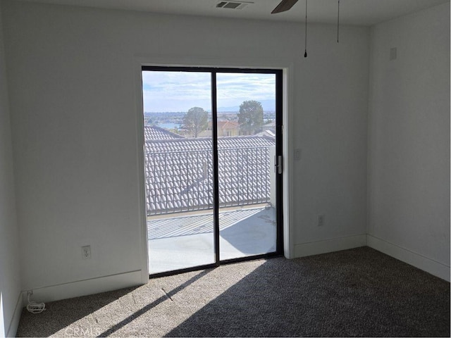 empty room with ceiling fan and dark colored carpet