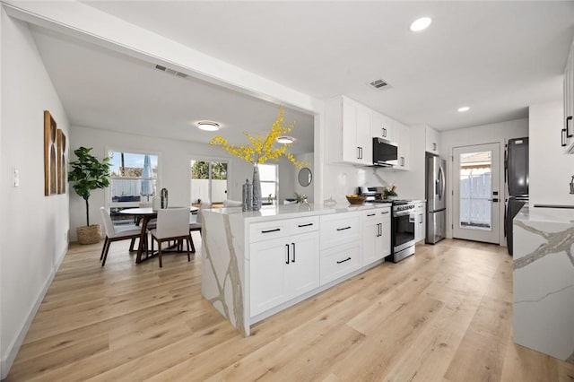 kitchen with a wealth of natural light, white cabinets, and appliances with stainless steel finishes