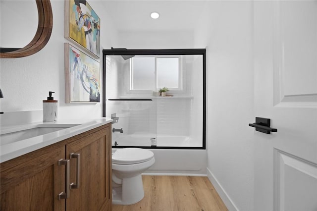 full bathroom featuring toilet, vanity, wood-type flooring, and combined bath / shower with glass door