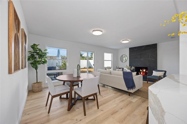 dining space featuring light wood-type flooring and a premium fireplace