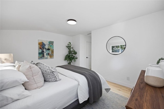 bedroom with lofted ceiling and light wood-type flooring