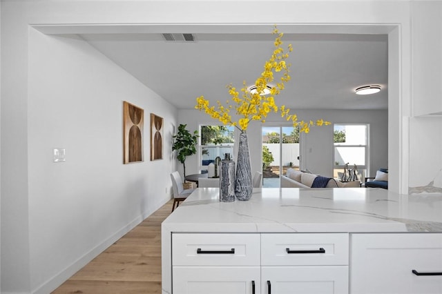 kitchen with light stone countertops, white cabinets, and light wood-type flooring