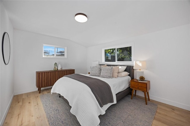 bedroom with vaulted ceiling, light hardwood / wood-style flooring, and multiple windows