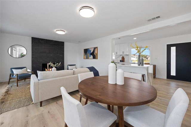 dining space featuring light wood-type flooring and a premium fireplace