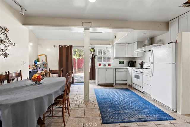 kitchen featuring white appliances, white cabinets, wall chimney exhaust hood, light tile patterned floors, and tasteful backsplash