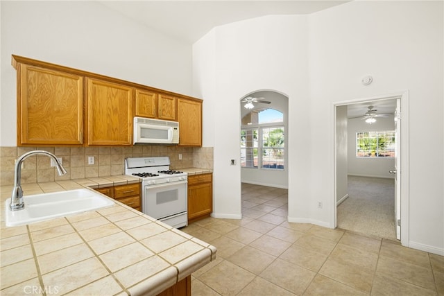 kitchen with tile counters, white appliances, sink, and light tile patterned floors