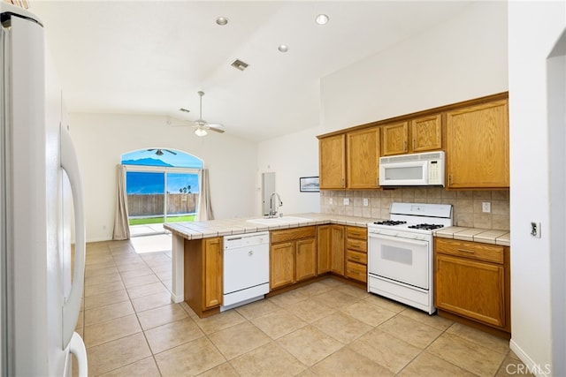 kitchen with kitchen peninsula, white appliances, sink, tile counters, and lofted ceiling