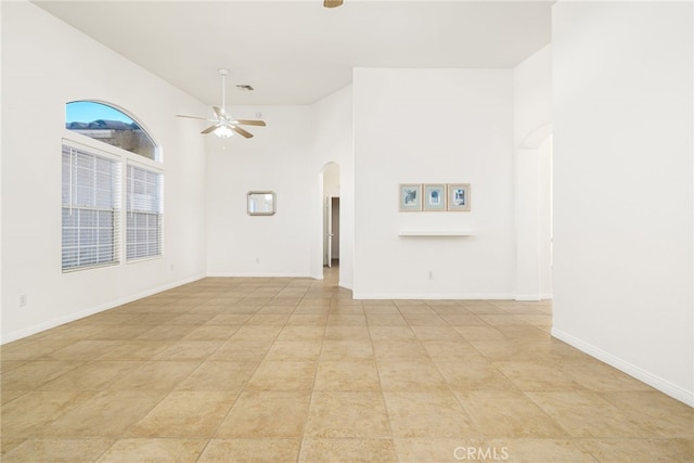 unfurnished living room with ceiling fan, a towering ceiling, and light tile patterned floors