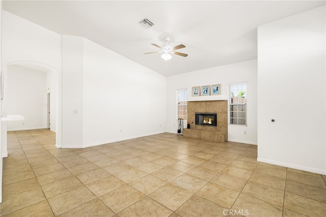 unfurnished living room with a tiled fireplace, ceiling fan, and light tile patterned flooring