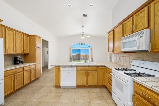 kitchen with decorative backsplash, white appliances, sink, tile countertops, and lofted ceiling