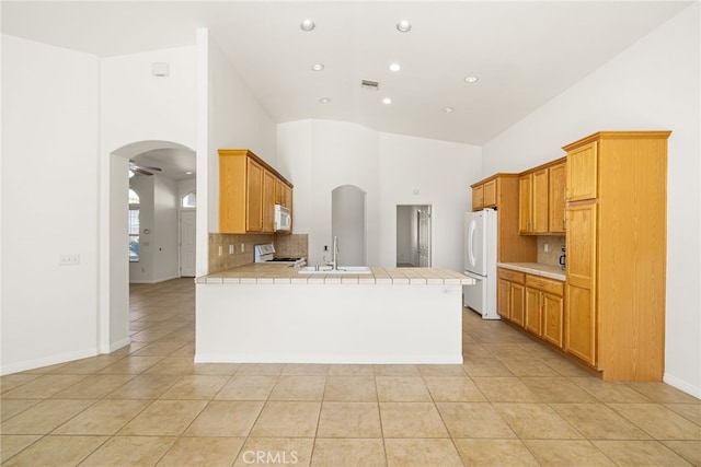 kitchen featuring ceiling fan, sink, kitchen peninsula, tile countertops, and white appliances