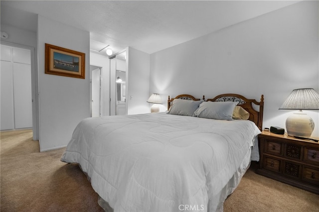 bedroom with ensuite bath and light colored carpet