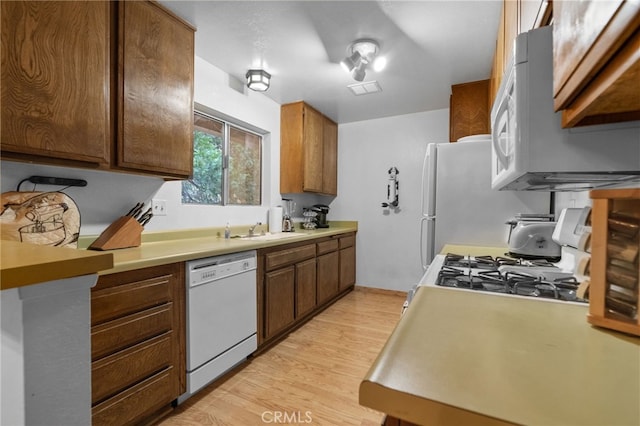 kitchen featuring light hardwood / wood-style flooring, white appliances, and sink