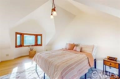 bedroom featuring vaulted ceiling and light wood-type flooring