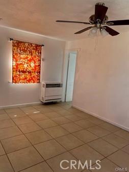 empty room with tile patterned floors, an AC wall unit, and ceiling fan