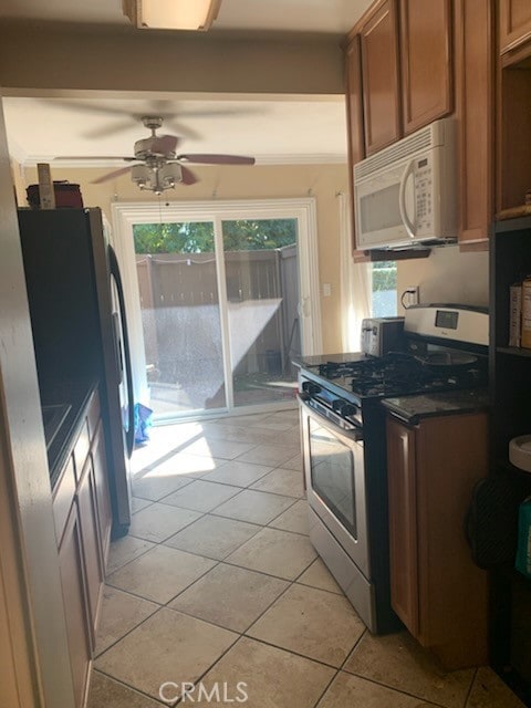 kitchen featuring ceiling fan, light tile patterned floors, ornamental molding, and gas range