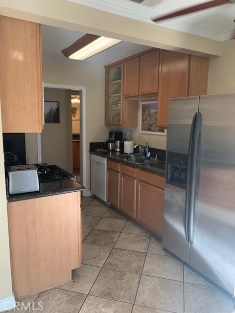 kitchen with sink, light tile patterned floors, dark stone countertops, dishwasher, and stainless steel fridge with ice dispenser