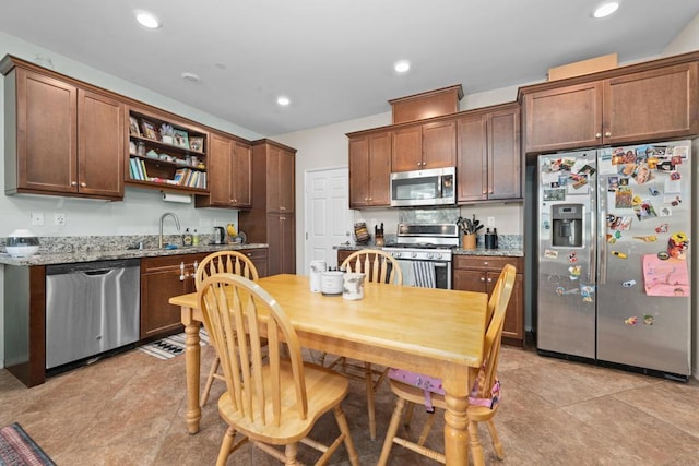 kitchen featuring light tile patterned flooring, appliances with stainless steel finishes, light stone counters, and sink