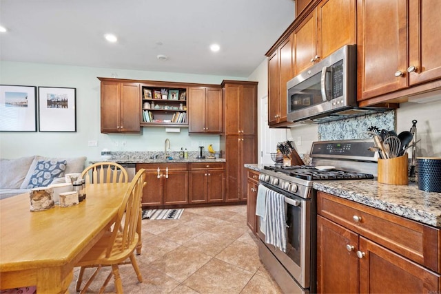 kitchen with light stone countertops, appliances with stainless steel finishes, tasteful backsplash, sink, and light tile patterned flooring