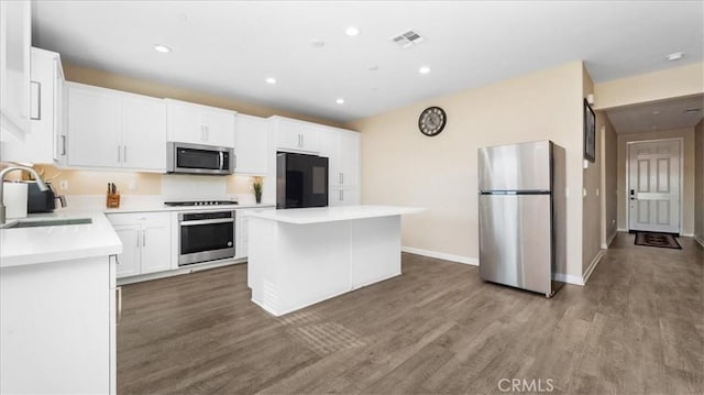 kitchen with sink, a center island, stainless steel appliances, wood-type flooring, and white cabinets