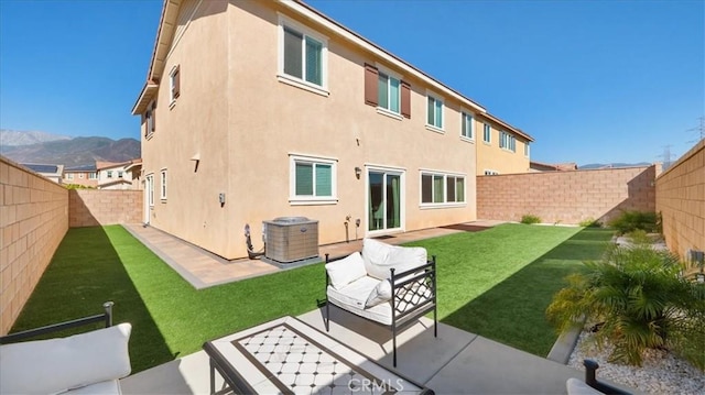 rear view of house with an outdoor hangout area, central air condition unit, a patio area, a mountain view, and a yard