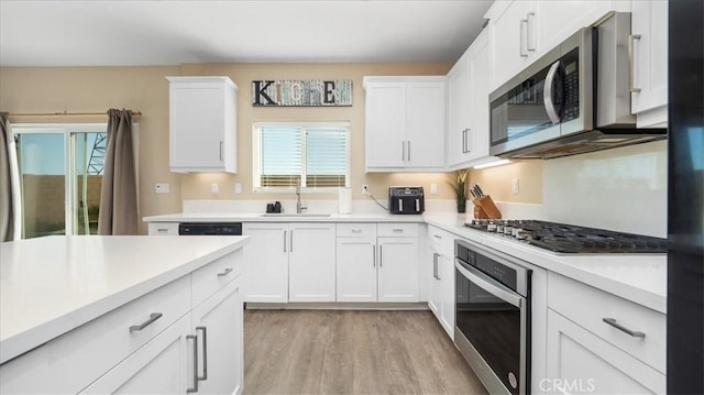 kitchen featuring sink, white cabinetry, stainless steel appliances, and light hardwood / wood-style flooring