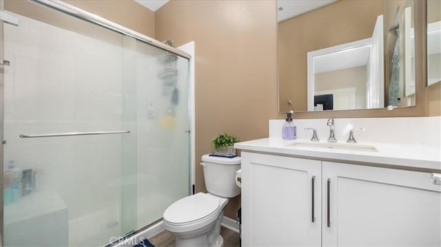 bathroom featuring vanity, toilet, and a shower with door