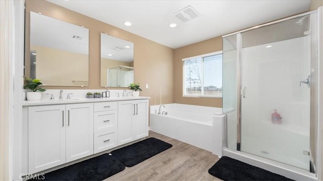 bathroom with plus walk in shower, wood-type flooring, and vanity