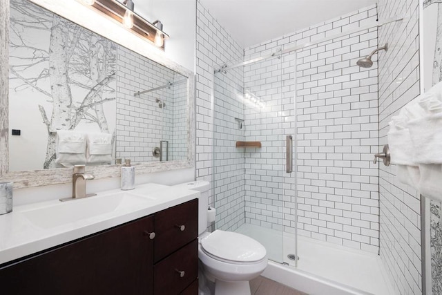 bathroom featuring vanity, toilet, and a shower with shower door