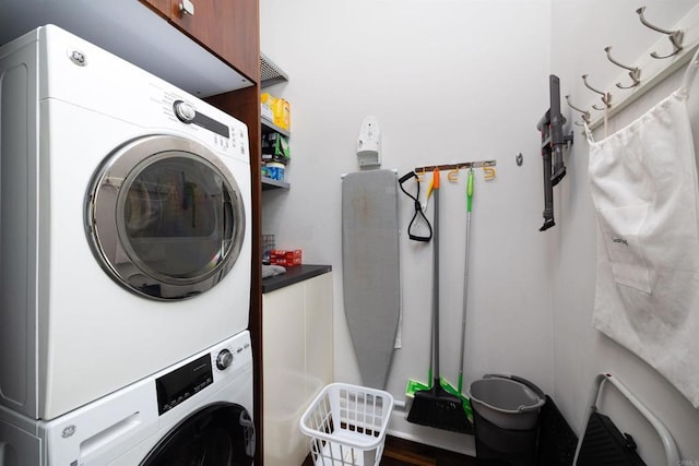 clothes washing area featuring cabinets and stacked washer and dryer