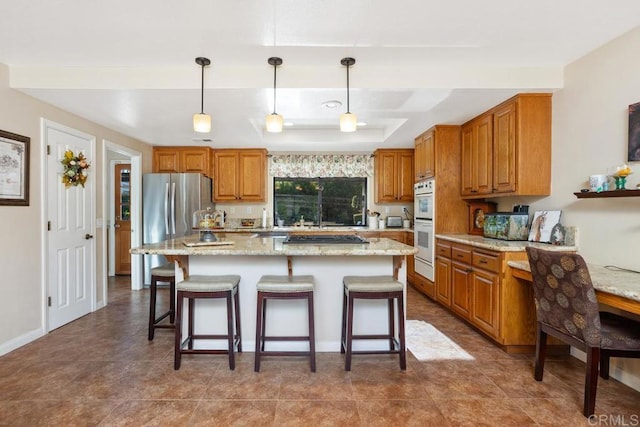 kitchen with light stone counters, a center island, stainless steel appliances, and decorative light fixtures