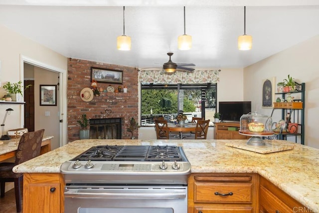 kitchen featuring ceiling fan, light stone counters, hanging light fixtures, and stainless steel range with gas stovetop