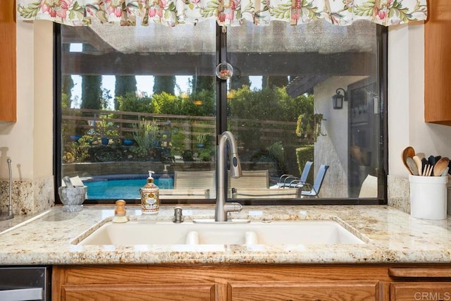 exterior space featuring dishwasher, light stone counters, and sink