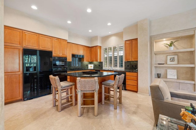 kitchen with a kitchen breakfast bar, tasteful backsplash, black appliances, dark stone countertops, and a center island