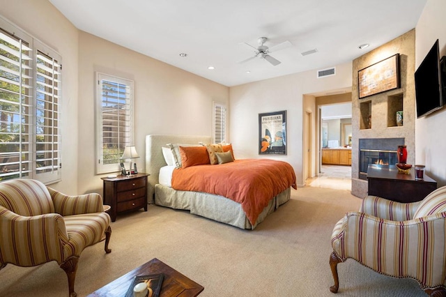 bedroom with ceiling fan, a large fireplace, and light carpet