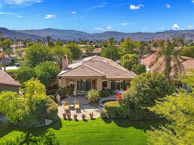 exterior space with a mountain view, a patio area, and a lawn