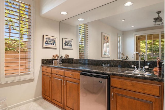 kitchen featuring dishwasher, dark stone countertops, and sink