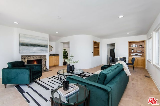 living room with a premium fireplace, built in features, and light parquet floors