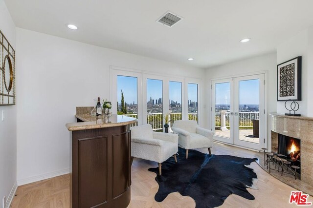 sitting room featuring a premium fireplace, french doors, and light parquet floors