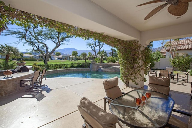 view of pool featuring a mountain view, a bar, ceiling fan, and a patio area