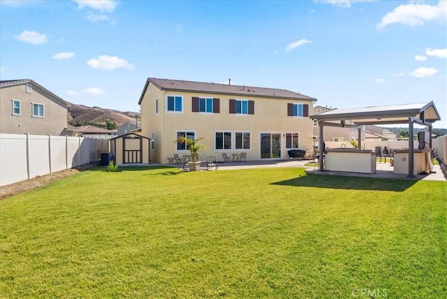 back of house featuring a lawn, a patio area, a storage shed, and a jacuzzi