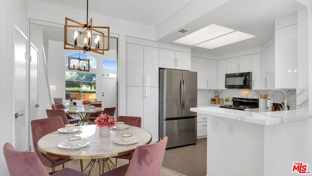 kitchen featuring black appliances, hanging light fixtures, decorative backsplash, white cabinetry, and a chandelier