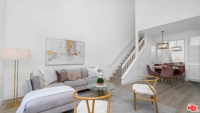 living room featuring a high ceiling, light hardwood / wood-style floors, and a notable chandelier