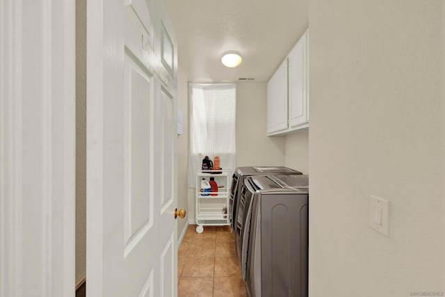 clothes washing area featuring cabinets, independent washer and dryer, and light tile patterned floors