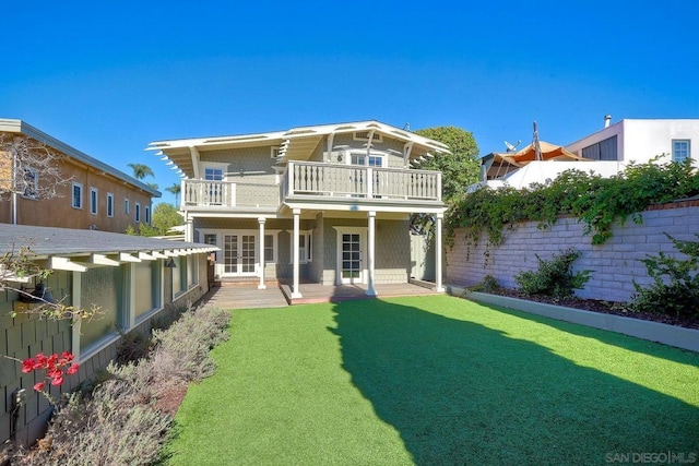 back of property featuring a lawn, a balcony, and french doors