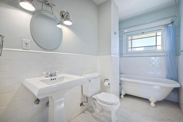 bathroom featuring tile patterned flooring, a bathing tub, toilet, and tile walls