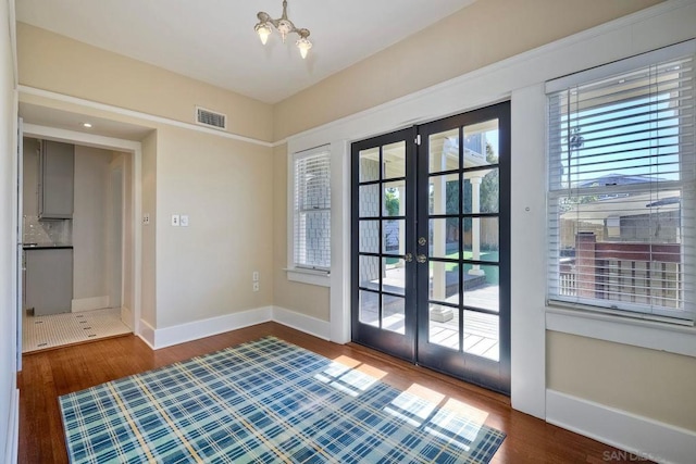 doorway to outside with french doors, a chandelier, and dark hardwood / wood-style floors